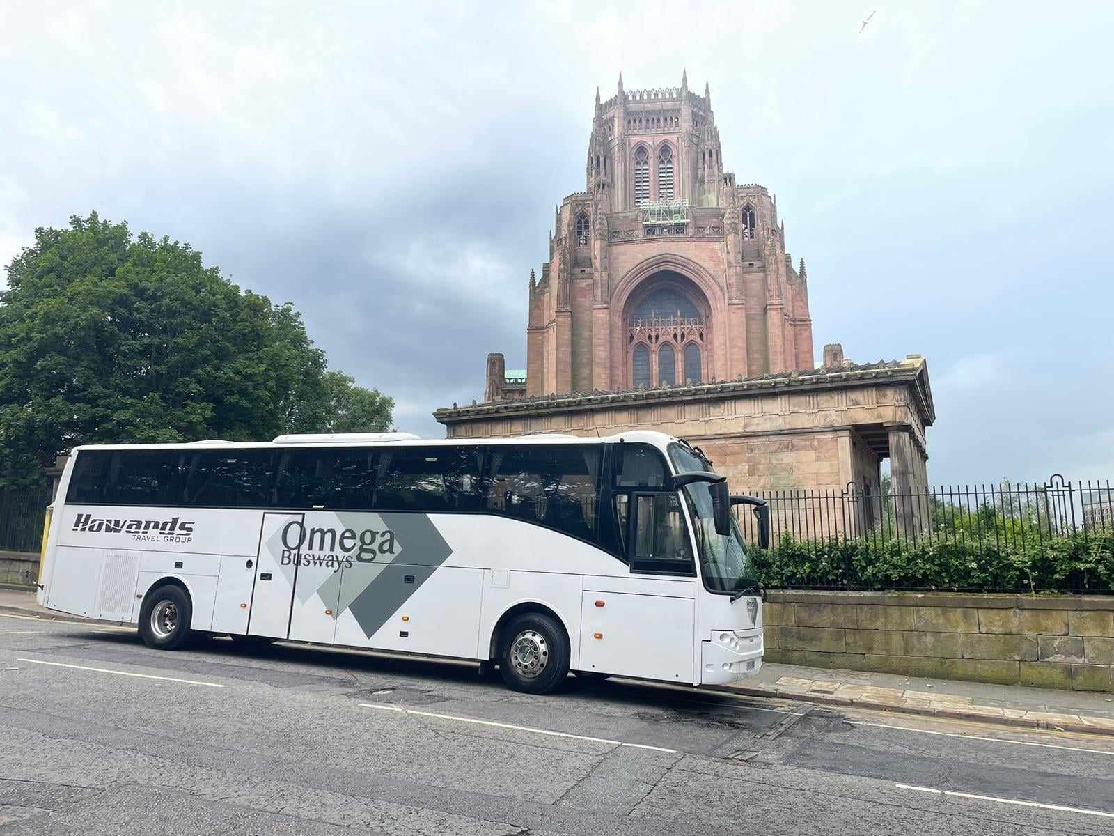 Omega Busways coach parked outside a cathedral.
